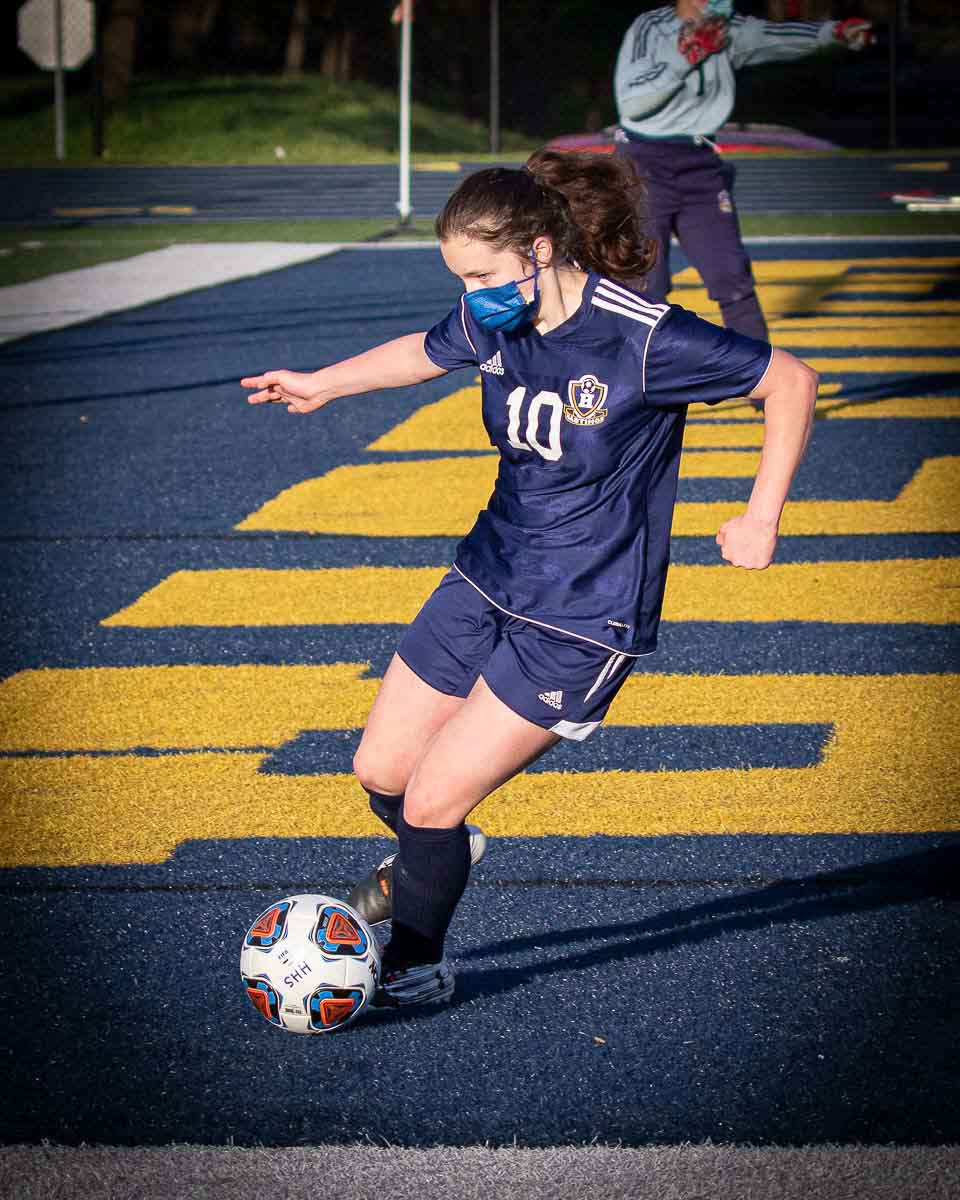 Girl kicking soccer ball on turf